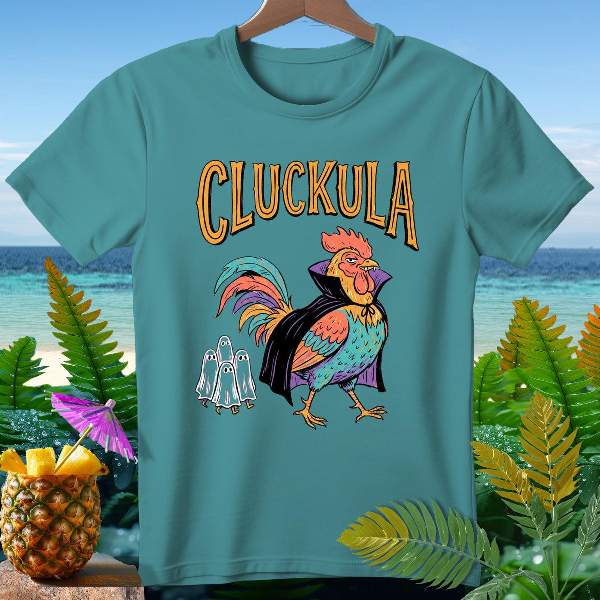 Teal t-shirt with "Cluckula" text and a rooster dressed as Dracula with ghosts.