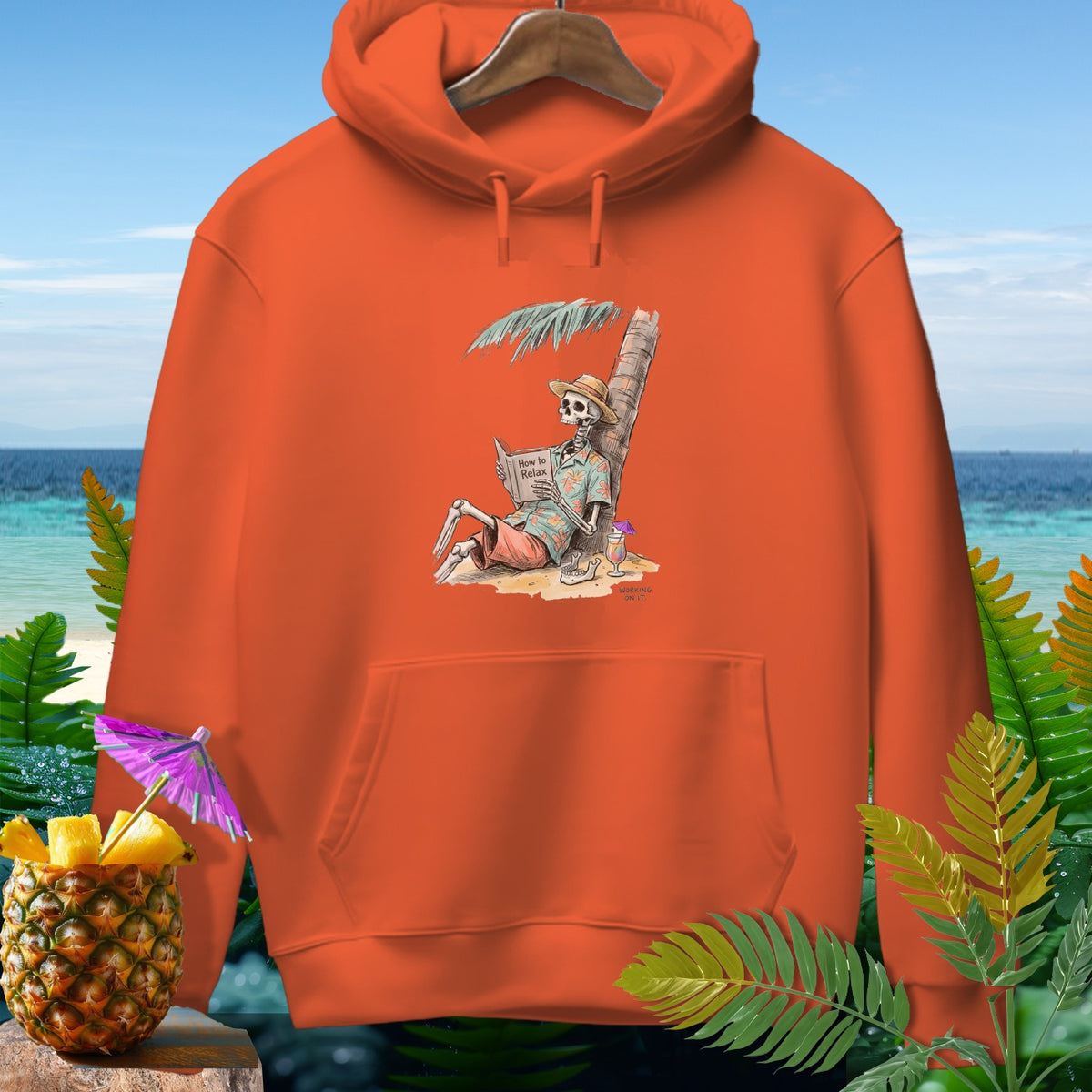 Orange hoodie with skeleton reading "How to Relax" on a beach.