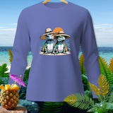 Two cartoon lizards wear straw hats in front of an ocean sunset on a purple long-sleeved shirt.