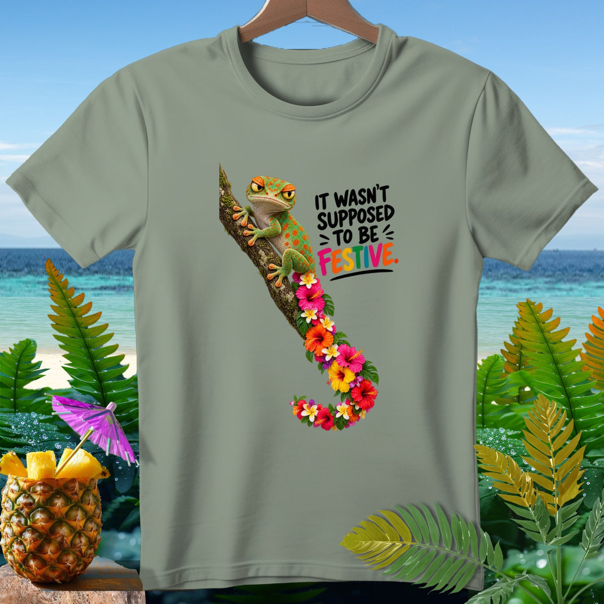 Green t-shirt with gecko on a branch and text "IT WASN'T SUPPOSED TO BE FESTIVE."