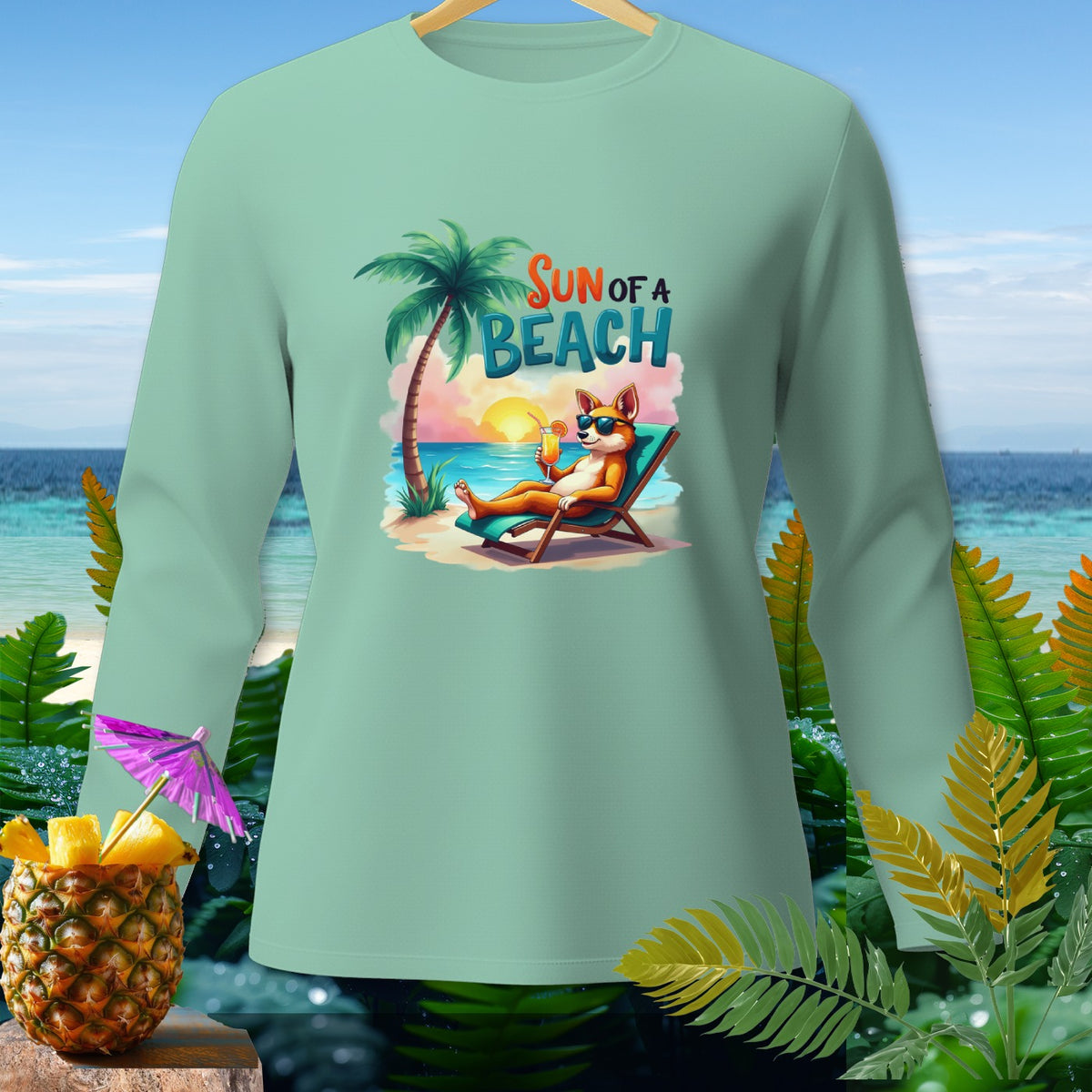 Mint long sleeve shirt with a cartoon fox relaxing on a beach with text "Sun of a Beach".