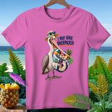 Pink t-shirt with a pelican wearing a straw hat and sunglasses, holding a bag full of beach items, text says 