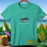 Teal t-shirt with a graphic of mountains, waves, moon, and text 