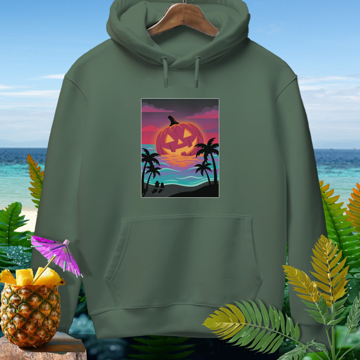 Green hoodie featuring a Halloween pumpkin graphic on a tropical beach sunset.