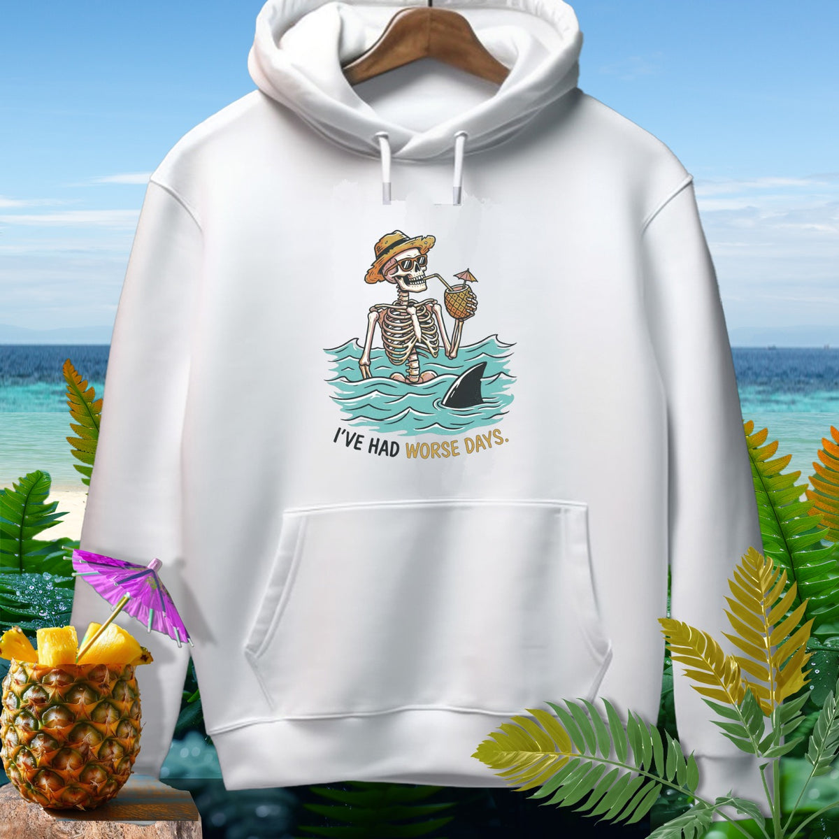 White hoodie with skeleton in water, shark fin, pineapple drink, and text "I'VE HAD WORSE DAYS."