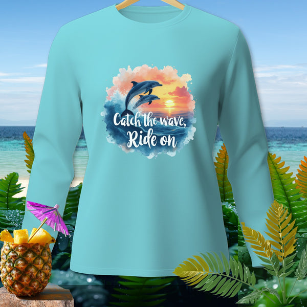 Light blue long-sleeve shirt with dolphins jumping over waves and text "Catch the wave, Ride on".