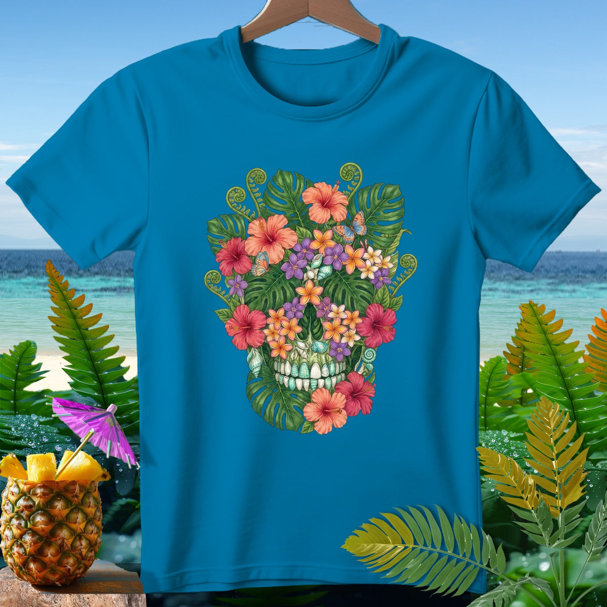 Blue t-shirt with a floral skull design and tropical background.