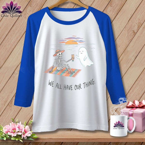Raglan shirt with skeleton and ghost on beach with text "We All Have Our Thing."