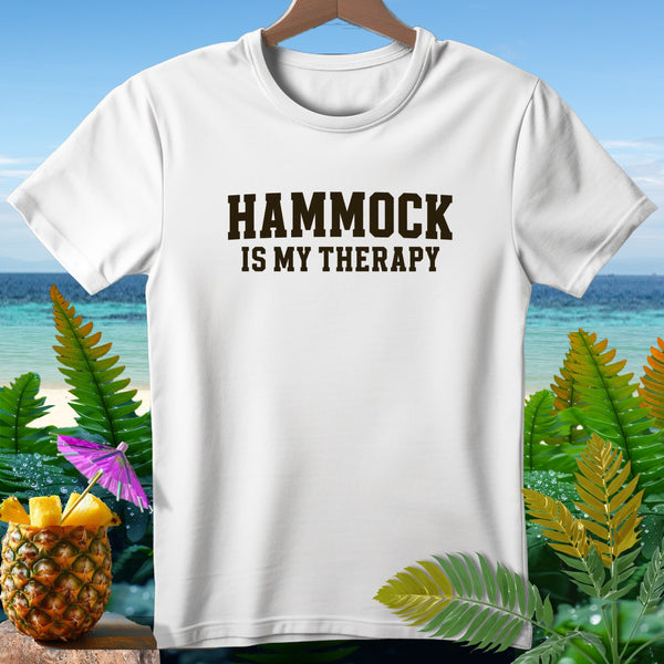 White t-shirt with text "HAMMOCK IS MY THERAPY" on a beach background.