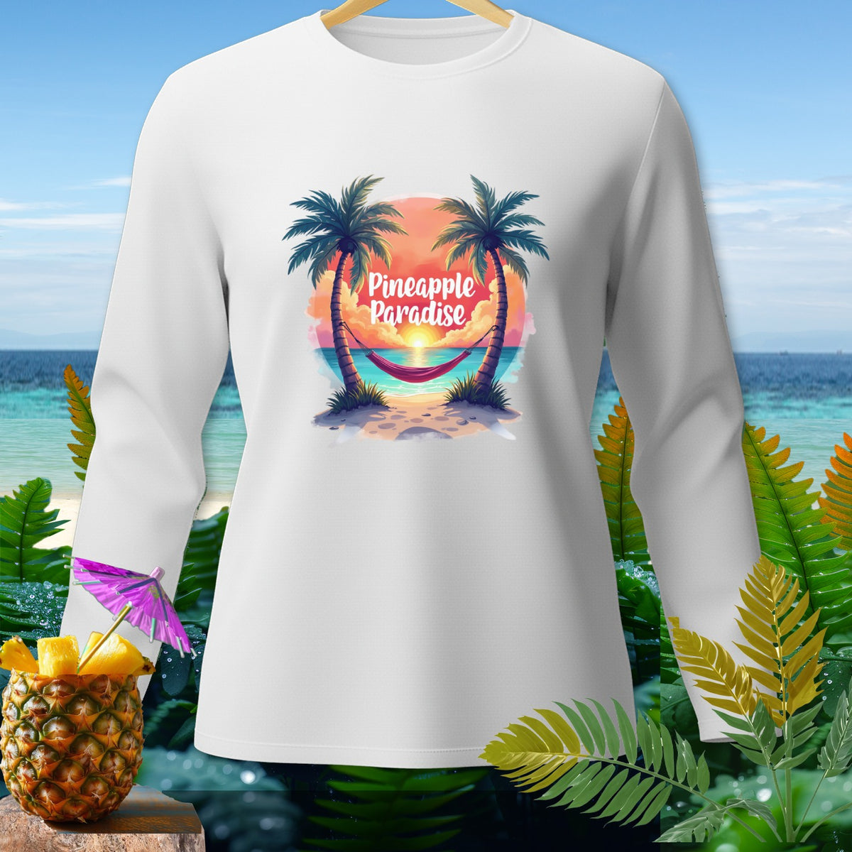 White long-sleeve shirt with "Pineapple Paradise" graphic of a beach sunset.