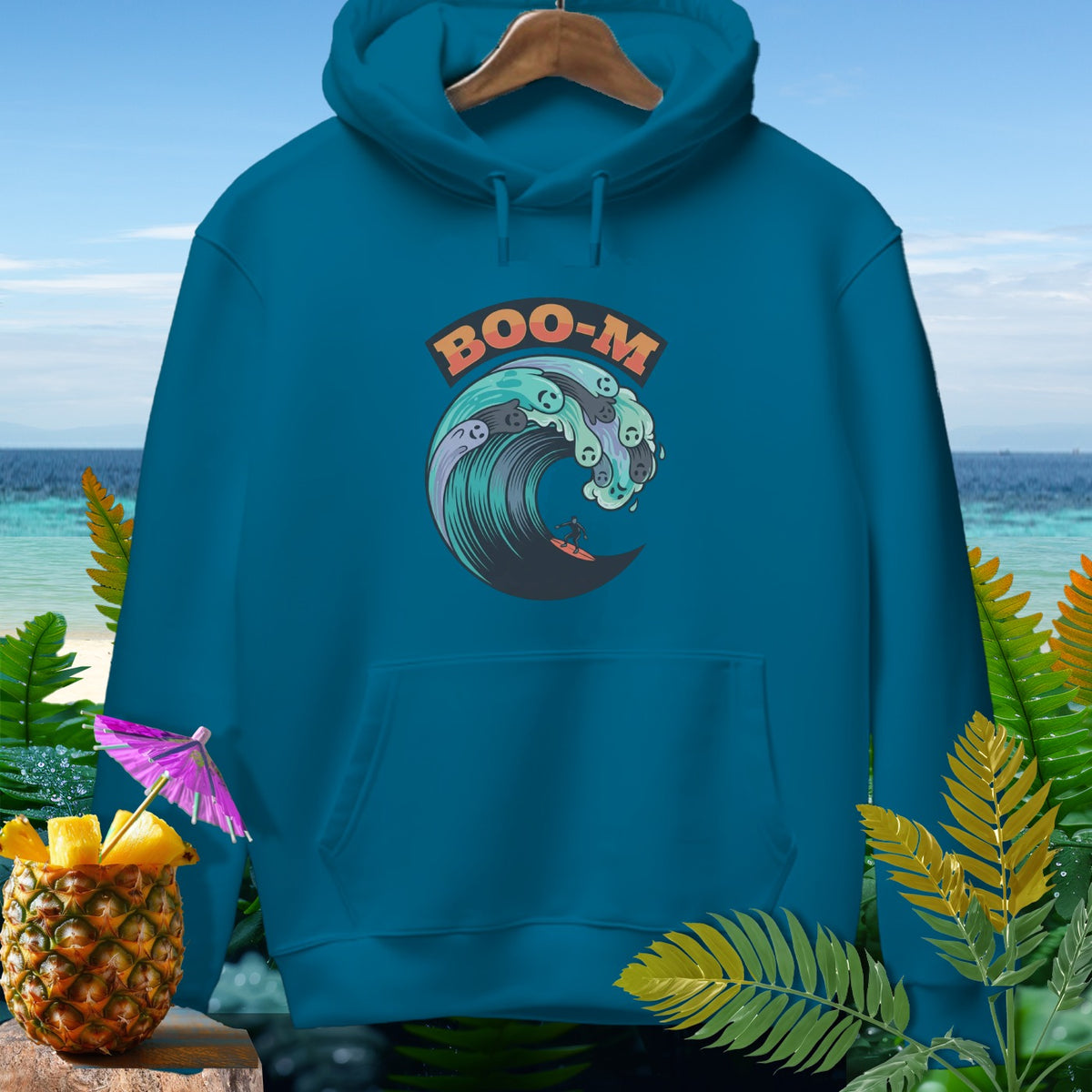 Teal hoodie with "BOO-M" text above a surfing wave graphic with skull elements.