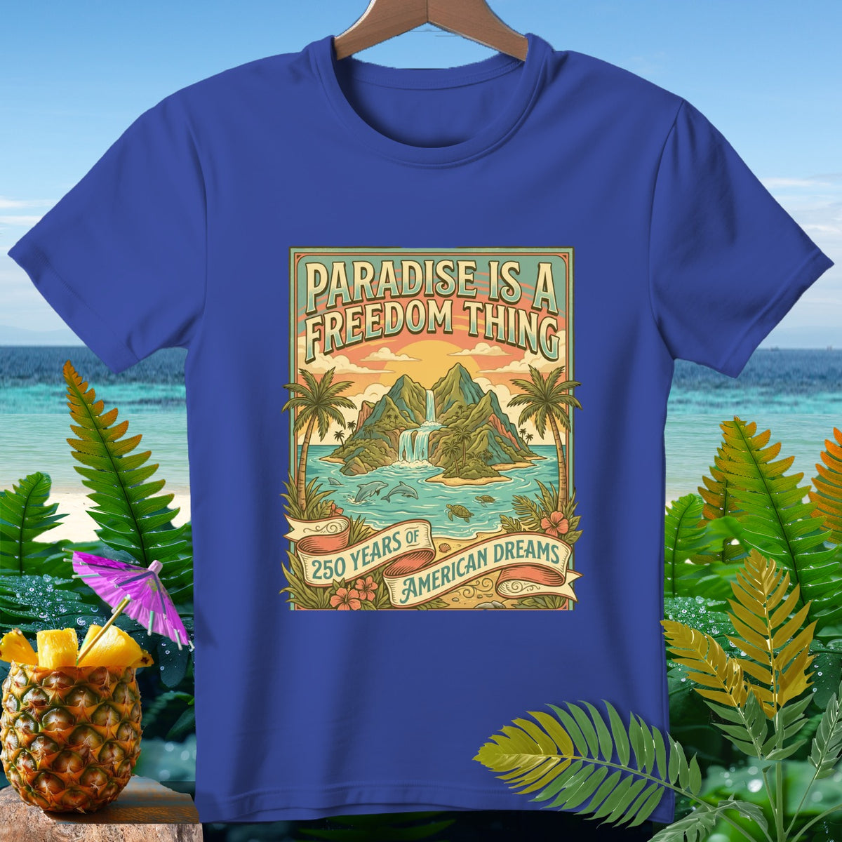 Blue t-shirt with island scene graphic reading "Paradise is a Freedom Thing" and "250 Years of American Dreams."