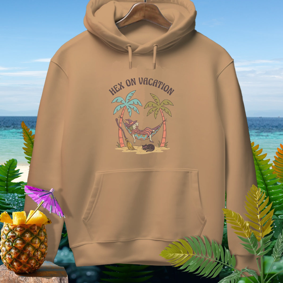 Tan hoodie with "Hex on Vacation" graphic featuring a witch in a hammock and a cat.