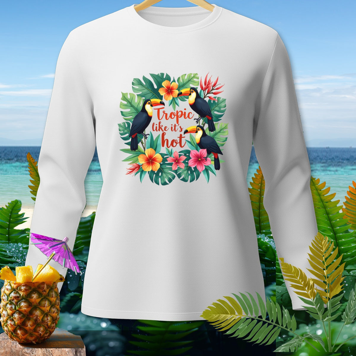 White long-sleeve shirt with a tropical design featuring toucans, flowers, and the text "Tropic like it's hot."