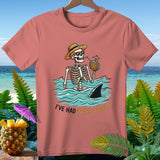 Skeleton with straw hat in water with shark fin, drinking from pineapple.