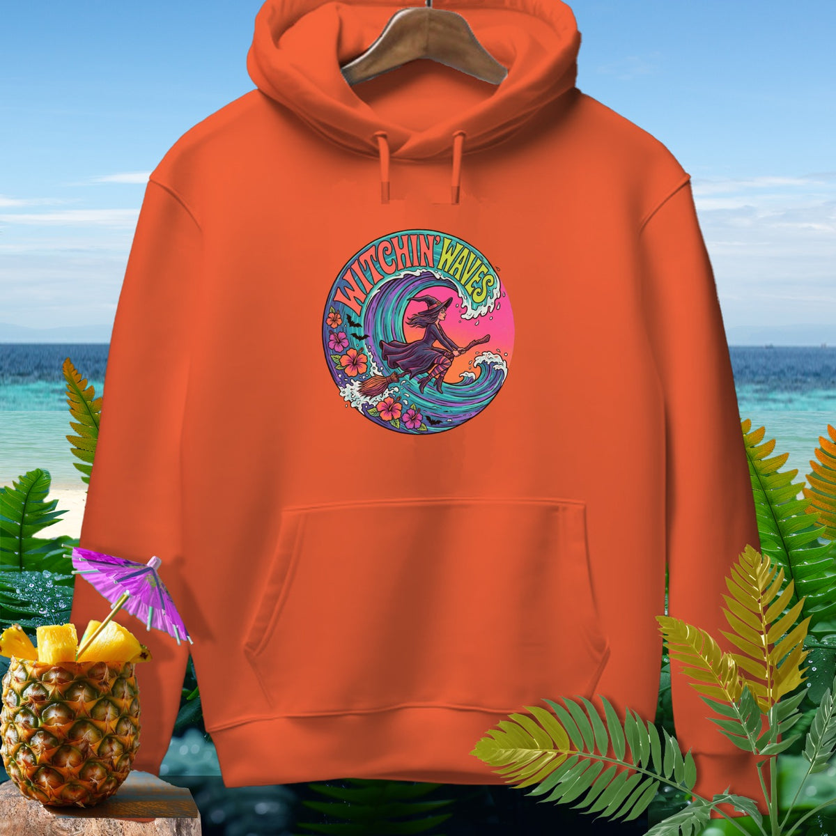 Orange hoodie with "Witchin' Waves" graphic of a witch surfing a wave.