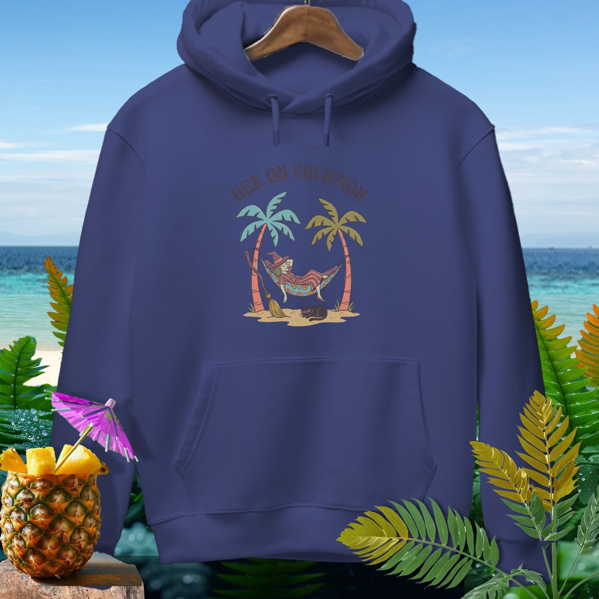 Dark blue hoodie with a witch in a hammock and the text "Hex On Vacation".