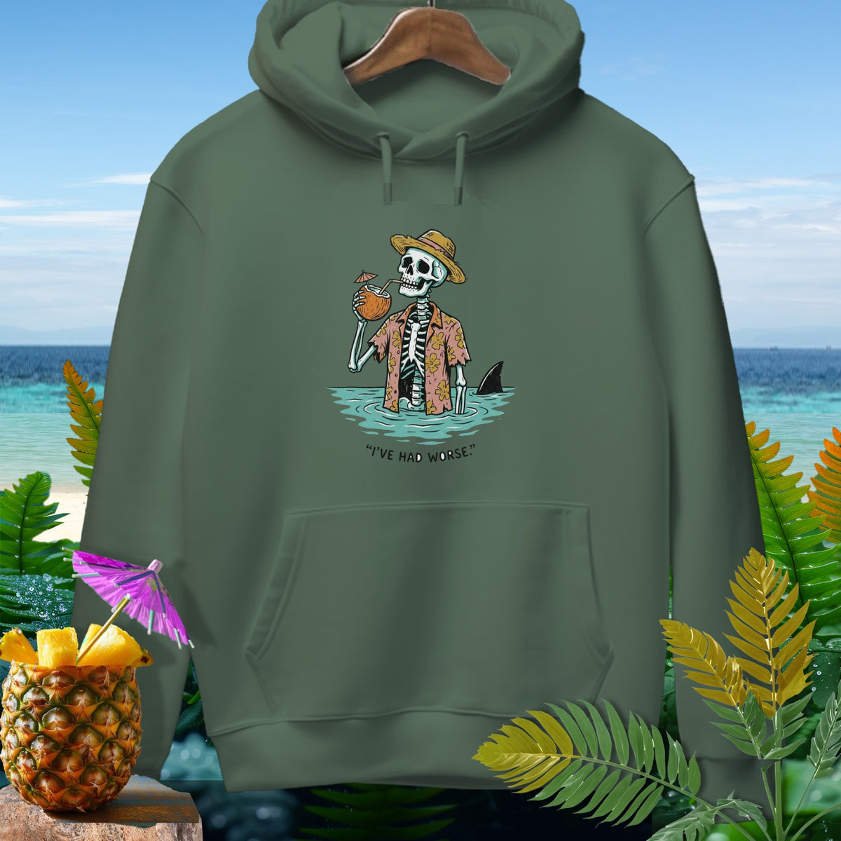 Green hoodie with skeleton in ocean, straw hat, drinking coconut, shark fin, and text "I'VE HAD WORSE."