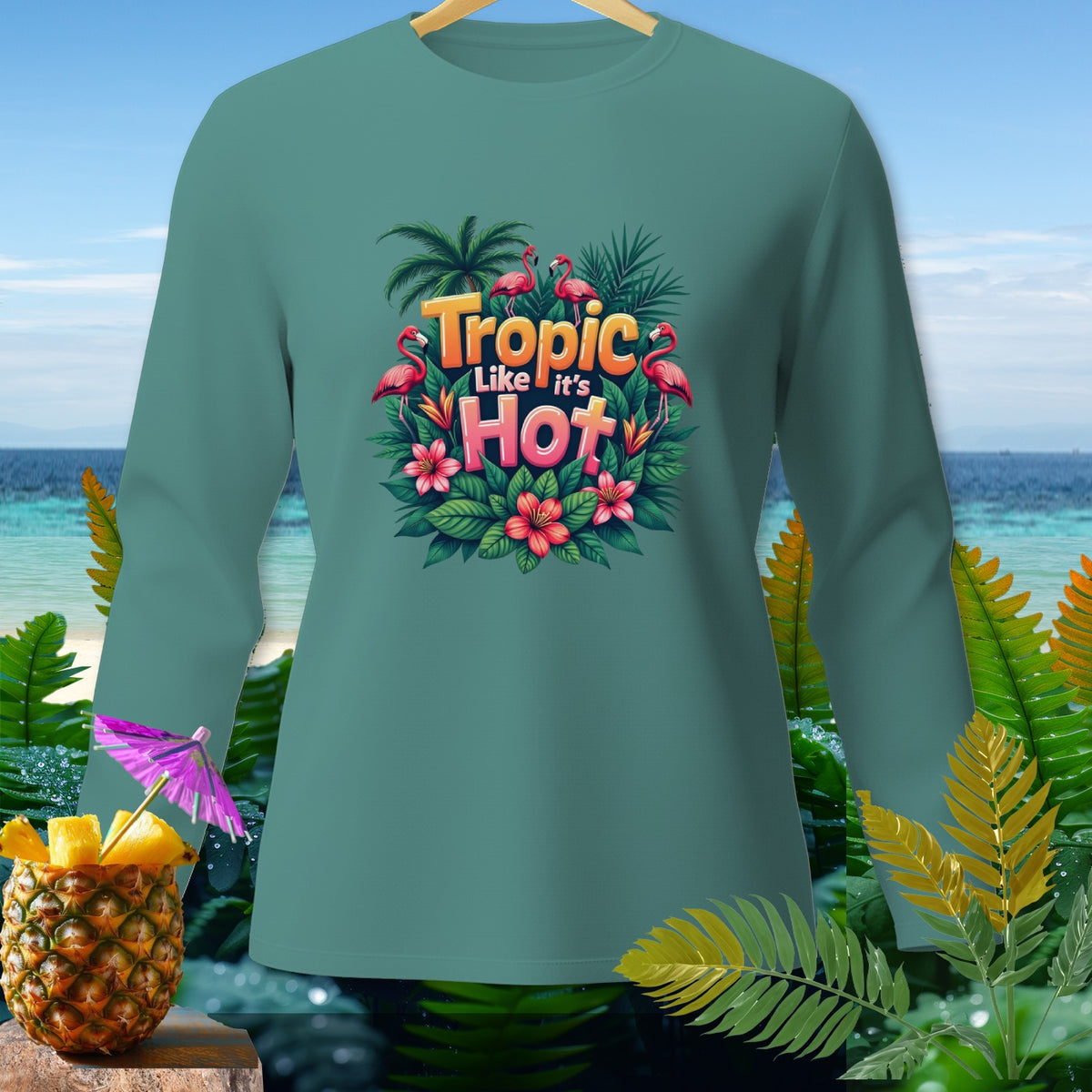 Teal long-sleeve shirt with "Tropic Like It's Hot" text, flamingos, and tropical leaves graphic.
