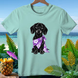 Black dachshund wearing purple floral bandana on light blue t-shirt with tropical background.