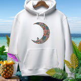 White hoodie with floral moon design and surfer silhouette, set against a beach backdrop.