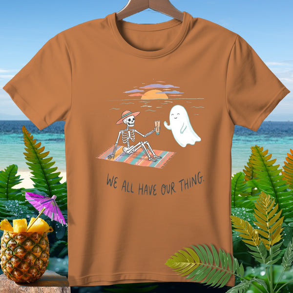 Skeleton and ghost on beach at sunset, text "We All Have Our Thing."