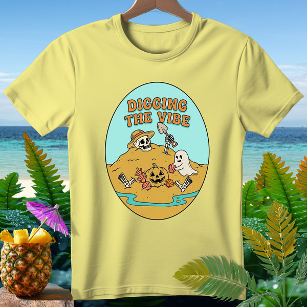 Yellow t-shirt with oval graphic of skeleton, ghost, pumpkin, and text "DIGGING THE VIBE".