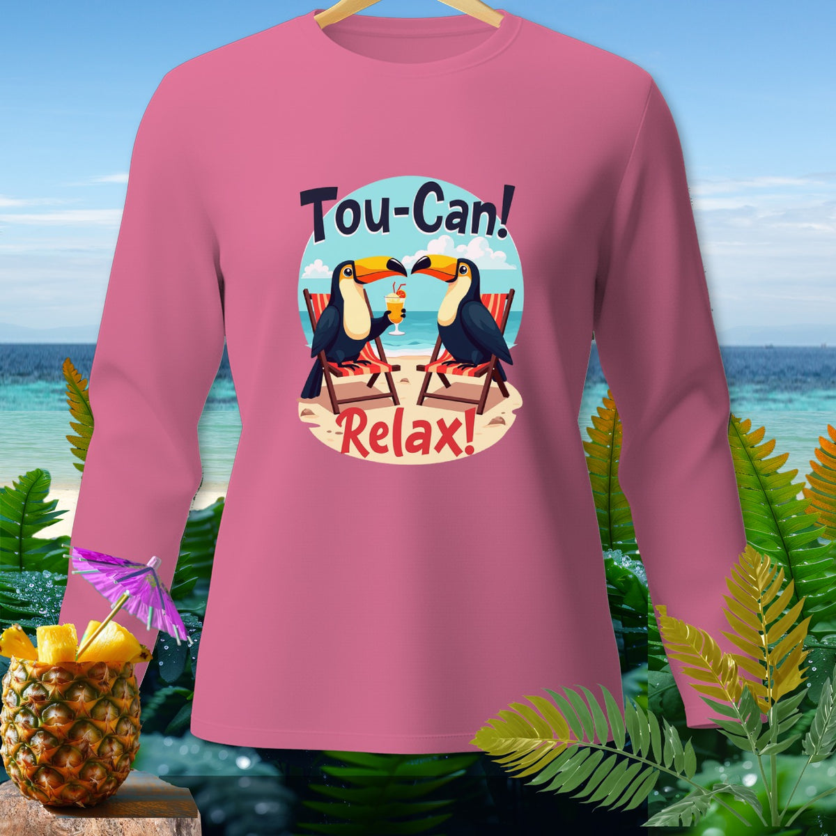Pink long-sleeve shirt with toucans, beach, and text "Tou-Can! Relax!"
