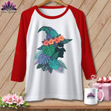 White raglan t-shirt with witch silhouette and tropical foliage graphic.