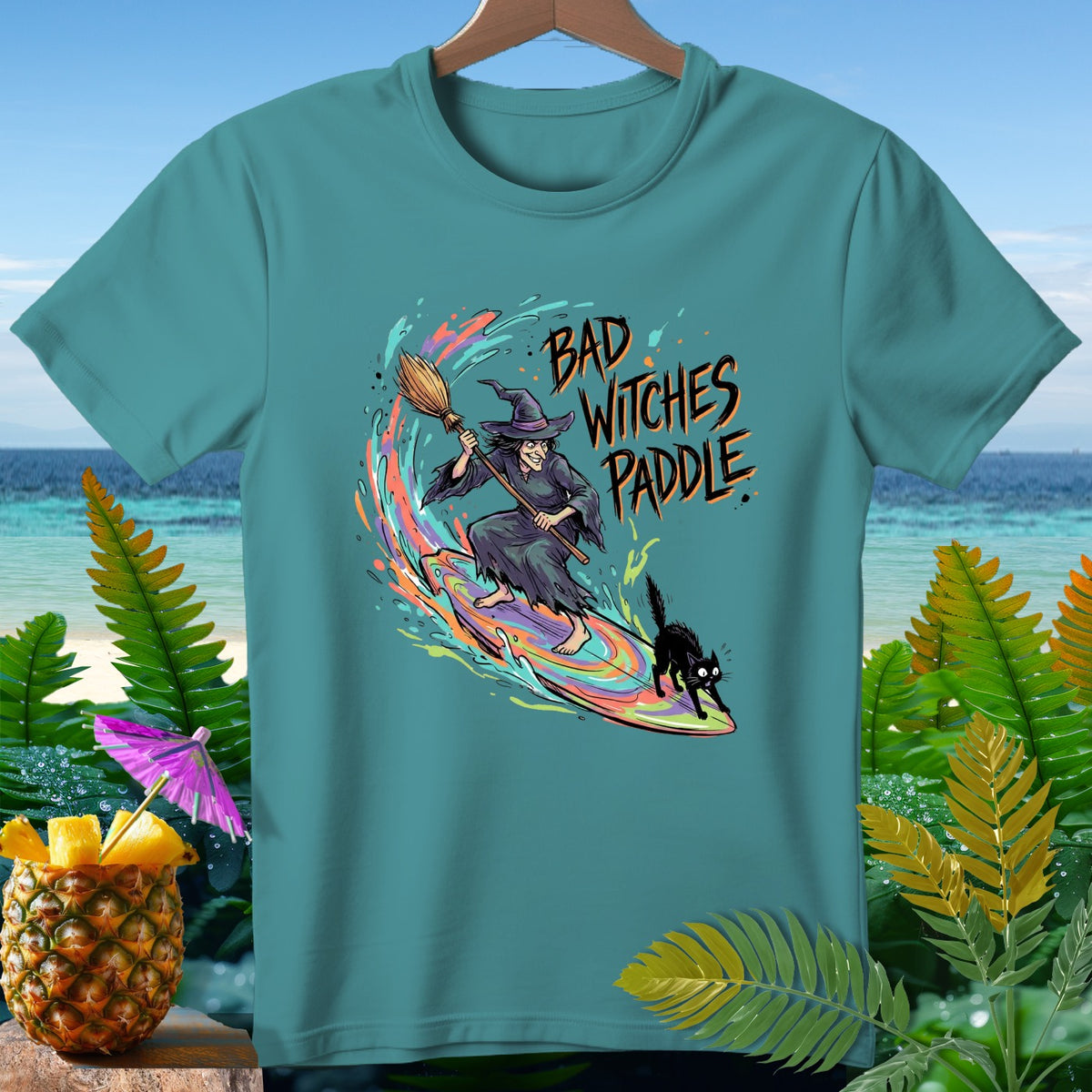 Teal t-shirt with witch, black cat, and text "BAD WITCHES PADDLE".