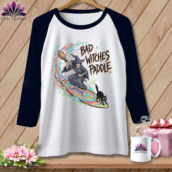 White raglan t-shirt with a witch, black cat, and "Bad Witches Paddle" text.