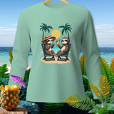 Light mint green long sleeve shirt featuring two sloths relaxing on a beach with drinks.