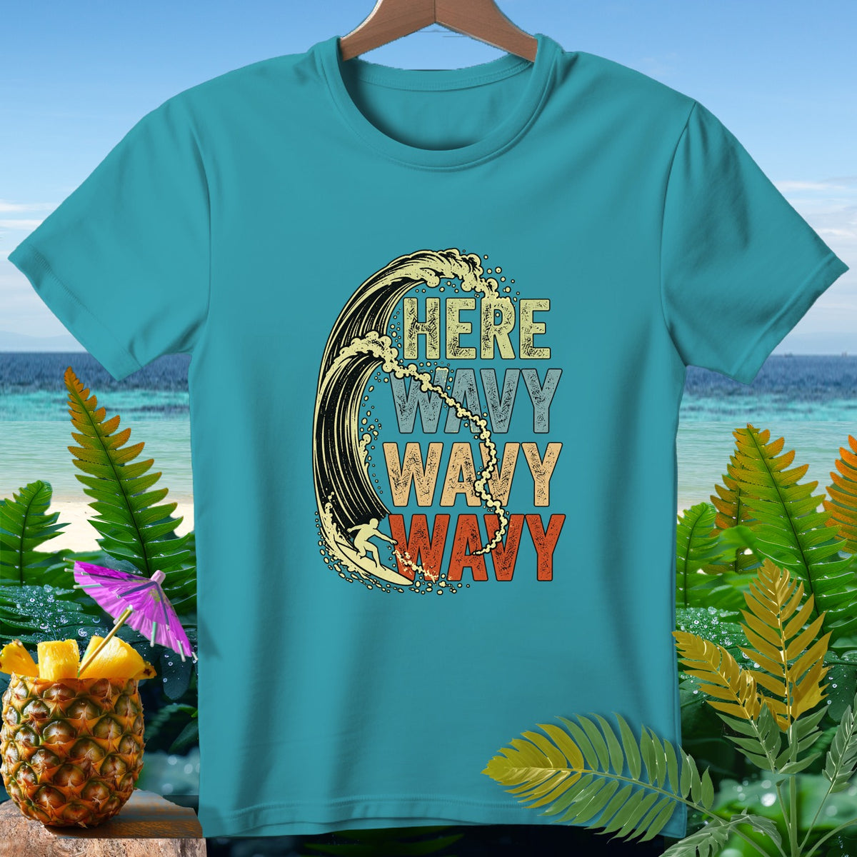 Teal t-shirt with graphic of surfer in wave and text "HERE WAVY WAVY WAVY".