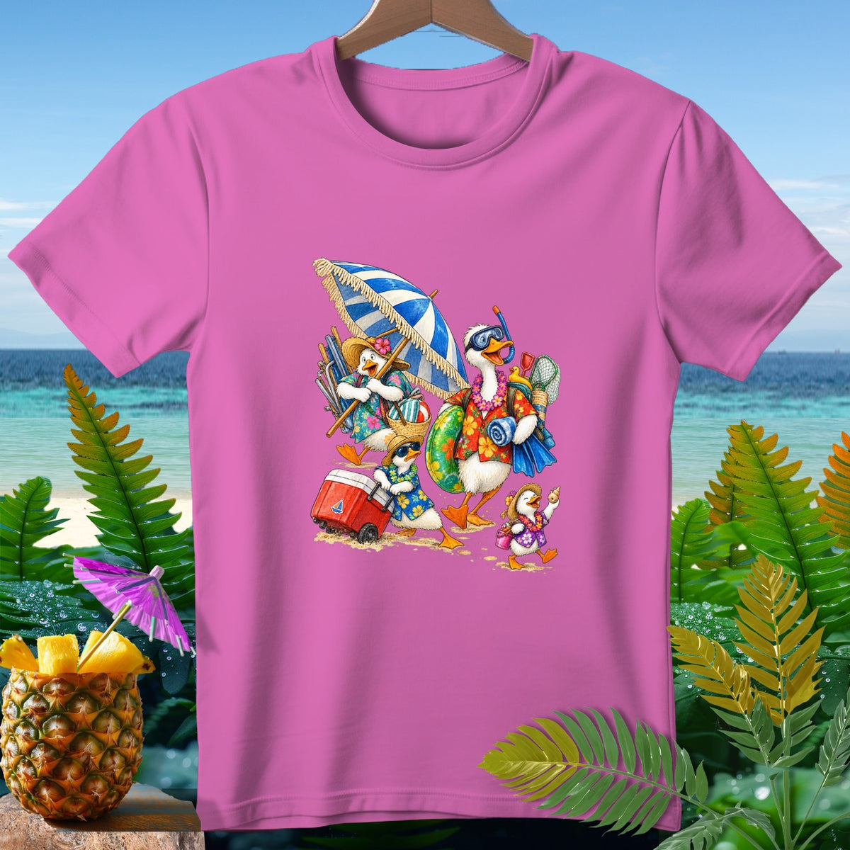 Pink t-shirt with cartoon ducks walking on a beach with umbrellas and a cooler.