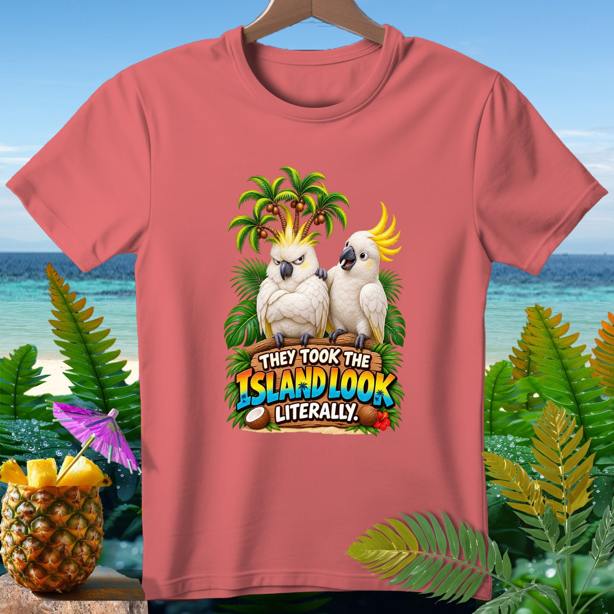 Coral t-shirt with cartoon cockatoos and text "They Took The Island Look Literally."