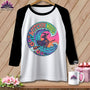 White t-shirt with black sleeves featuring a witch riding a broom over waves.