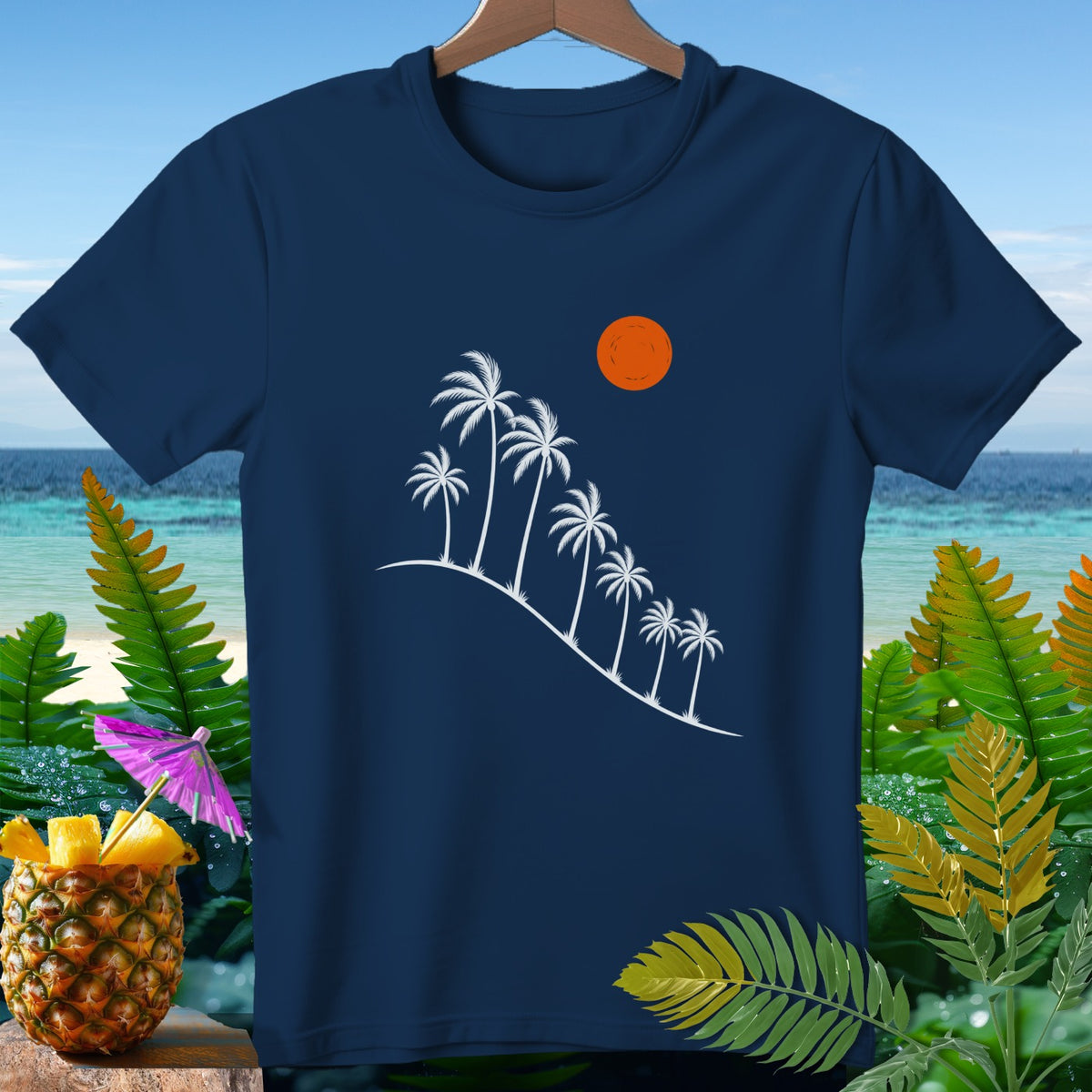 Navy t-shirt with white palm trees and sun graphic, surrounded by tropical foliage.