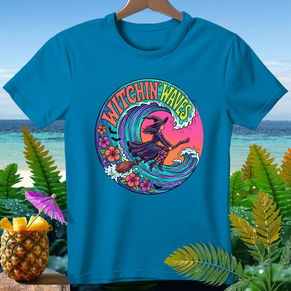 Teal t-shirt with "Witchin' Waves" graphic of a witch riding a broom through a wave.