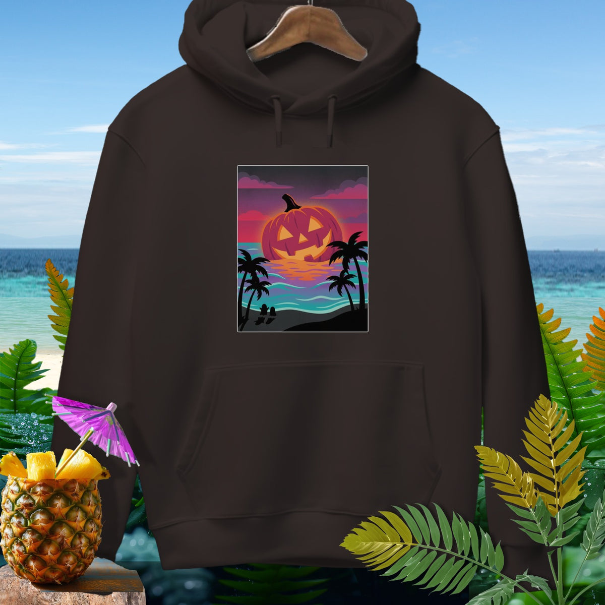 Dark brown hoodie with a glowing jack-o-lantern sunset graphic on a beach.