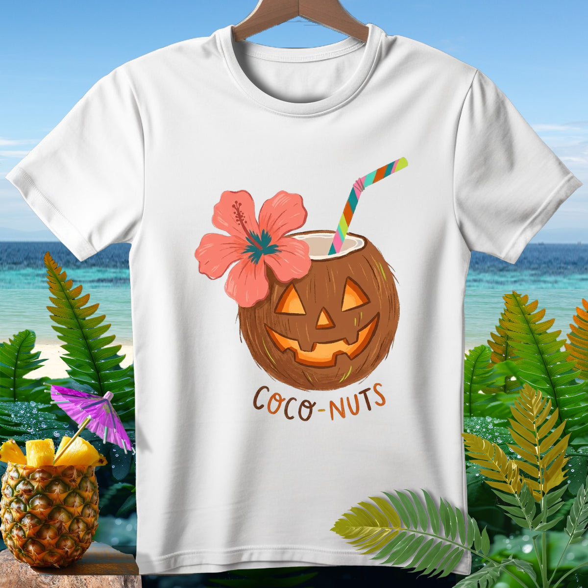 White t-shirt with a coconut carved like a jack-o'-lantern, a hibiscus flower, and text "Coco-Nuts".