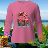 Pink long-sleeve shirt with two flamingos wearing hats and sunglasses on a tropical beach.