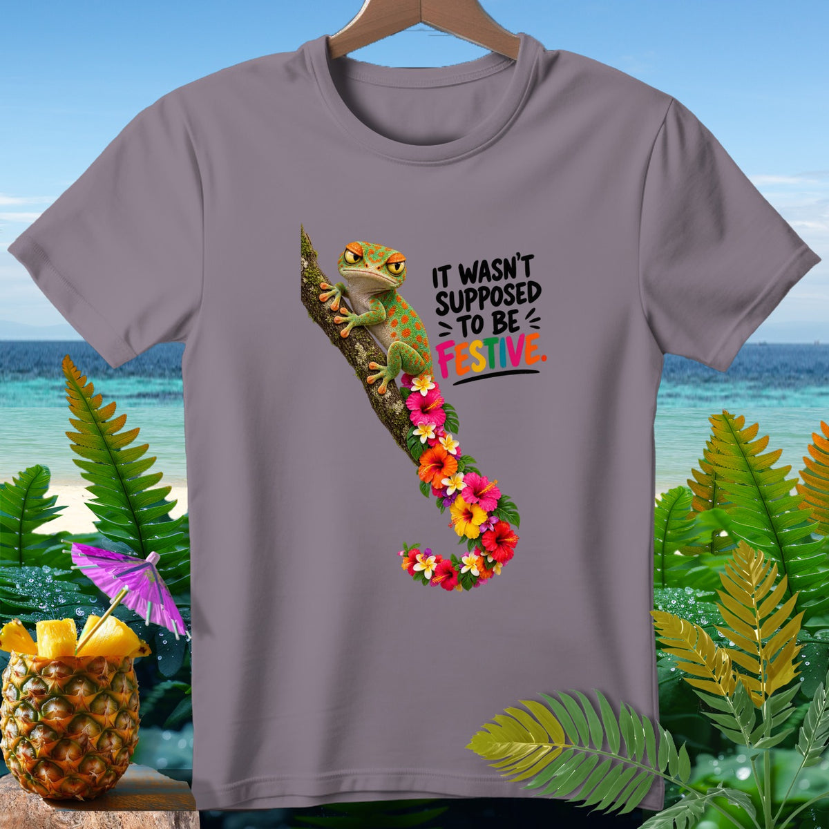 Gray t-shirt with a gecko, flowers, and text that says "It wasn't supposed to be festive."