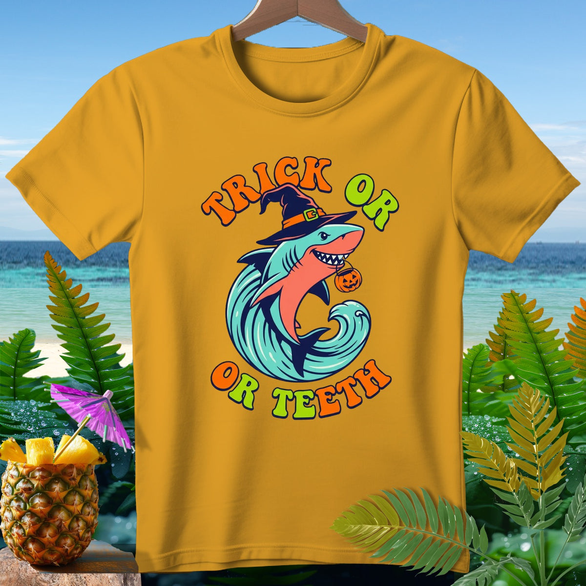 Yellow t-shirt with shark in witch hat, holding pumpkin, with "Trick or Teeth" text.