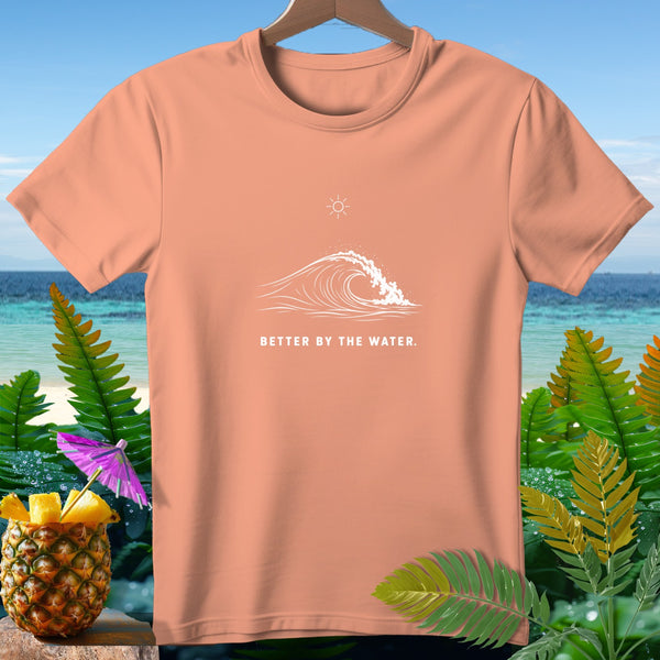 Peach t-shirt with white wave graphic and text "BETTER BY THE WATER."