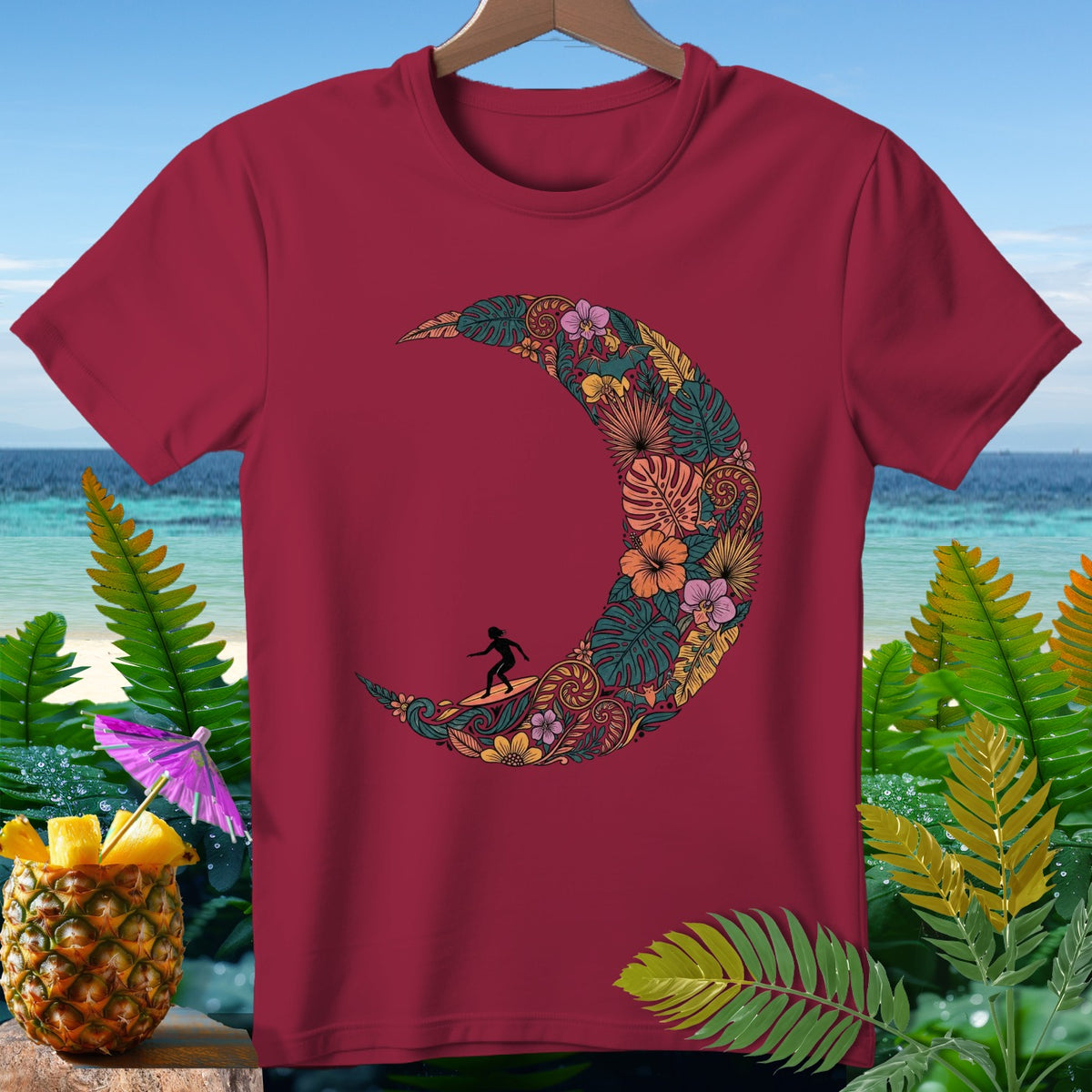 Maroon t-shirt with a colorful crescent moon design featuring a surfer and tropical foliage.