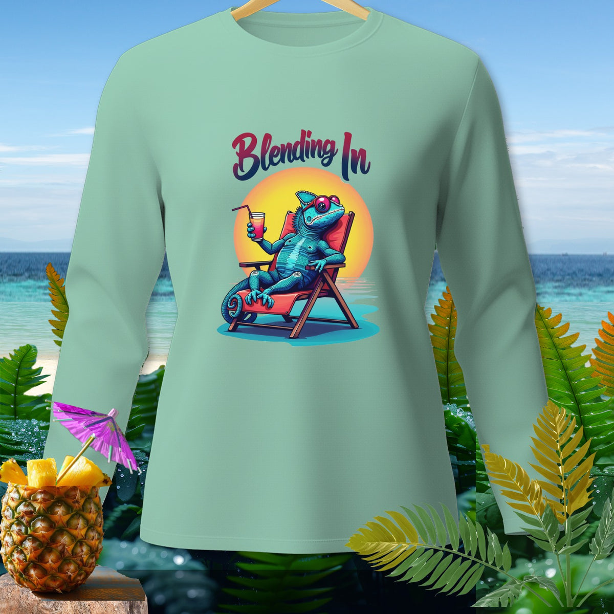 Light green long-sleeve shirt with a cartoon chameleon relaxing on a beach chair with text "Blending In".