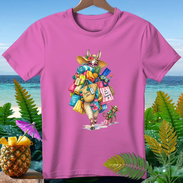 Pink t-shirt with llama wearing hat, carrying shopping bags and beach items.