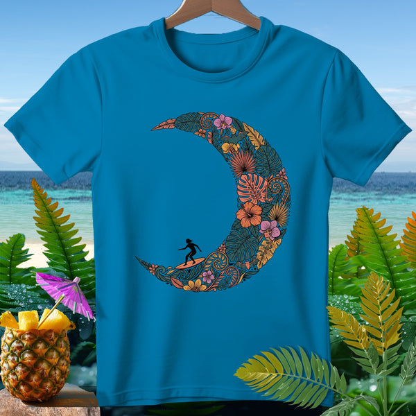 Blue t-shirt with a crescent moon design of tropical leaves, flowers, and a surfer.