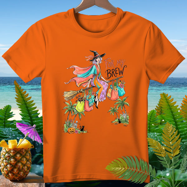 Orange t-shirt with witch flying on broomstick, text "FOR MY BREW", tropical Halloween scene.