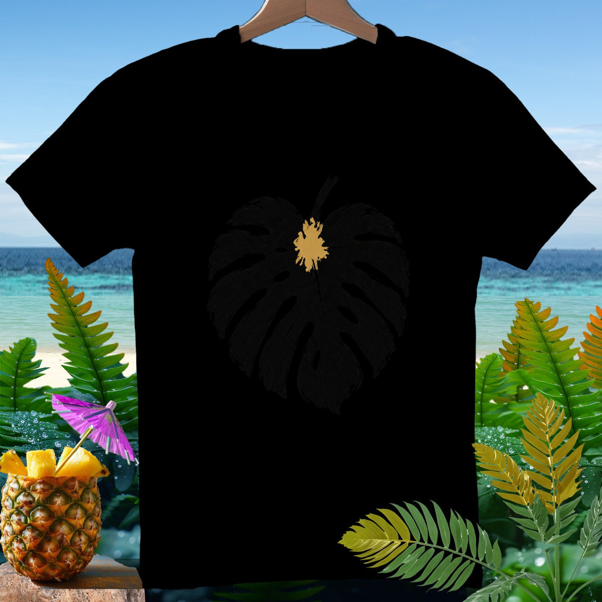 Black t-shirt with a golden leaf outline on a tropical beach backdrop.